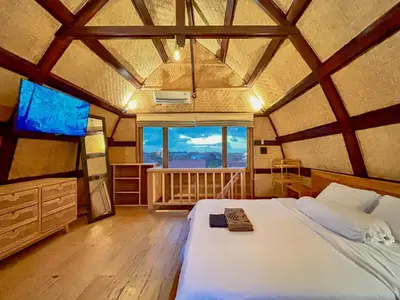 a bedroom with a large bed and a large window at Makaha Bungalow in Jimbaran