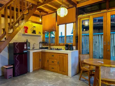 a kitchen with wooden cabinets and a sink and a table at Makaha Bungalow in Jimbaran