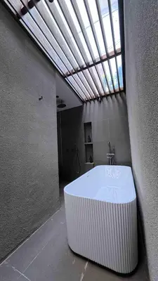 a large bath tub in a room with a window at Naiika villa in Seminyak