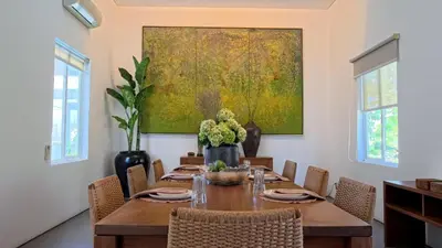 a dining room with a table and a painting on the wall at Naiika villa in Seminyak