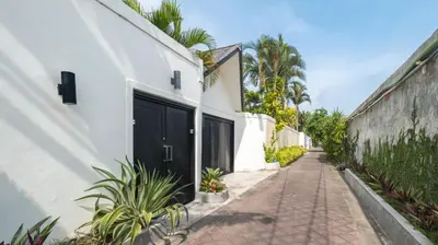 a white building with a black door and a sidewalk at Villa Merta Sari 8 by Villa Finder in Seminyak