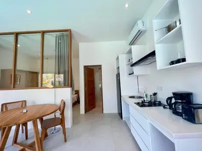 a kitchen with white counters and a wooden table at 1BR Tropical Villa With Pool - Canggu - Berawa in Canggu