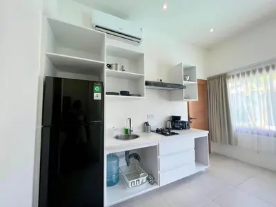 a kitchen with a black refrigerator and white cabinets at 1BR Tropical Villa With Pool - Canggu - Berawa in Canggu