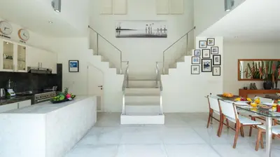 a kitchen with a staircase and a table with chairs at Villa Merta Sari 10 by Villa Finder in Seminyak