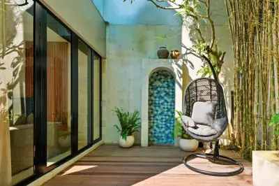a wicker chair sitting on a porch with plants at Luxury Villa in Berawa Beach 3BR - Canggu in Canggu