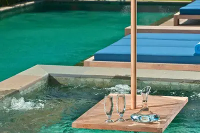 a pair of wine glasses sitting on a table next to a swimming pool at Calista Peaceful 4 BR Private Pool Villa in Canggu