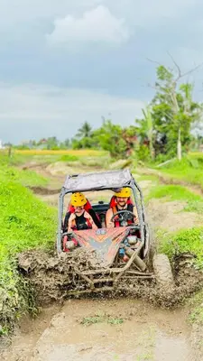 two people are riding in a dirt car on a dirt road at Bali Swing with Buggy adventure and white water Rafting in Pesanggaran