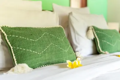 a green pillow and a yellow flower on a bed at Villa Alamanda, central location and close to restaurants in Seminyak