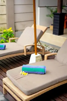 two lounge chairs and an umbrella on a patio at Villa Alamanda, central location and close to restaurants in Seminyak