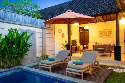 a patio with chairs and an umbrella next to a pool at Villa Alamanda, central location and close to restaurants in Seminyak