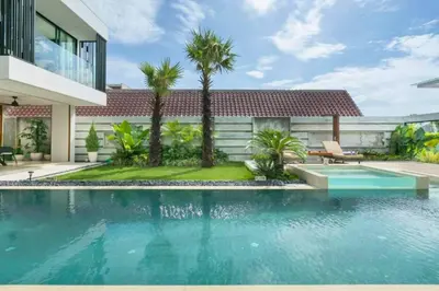 a swimming pool in front of a house with palm trees at Tanaya Luxury 4 BR Private Pool Villa in Canggu