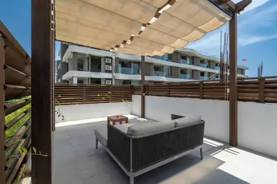 a patio with a couch on the roof of a building at Villa Hattala - Luxury Modern Villa in Prime Berawa with Air-Conditioned Living Space in Canggu