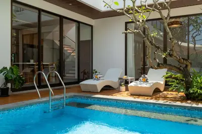 a pool in a house with chairs and a tree at Villa Hattala - Luxury Modern Villa in Prime Berawa with Air-Conditioned Living Space in Canggu