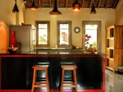 a kitchen with a bar with stools and a refrigerator at Bamboo Moon Villas in Sanur