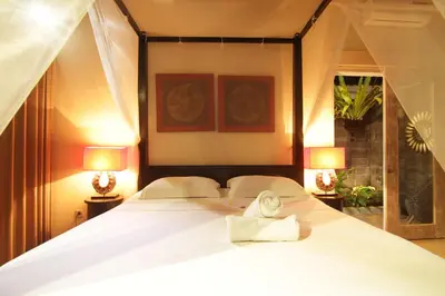 a bedroom with a white bed with two lamps at Bamboo Moon Villas in Sanur