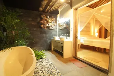 a bathroom with a tub and a sink and a bedroom at Bamboo Moon Villas in Sanur