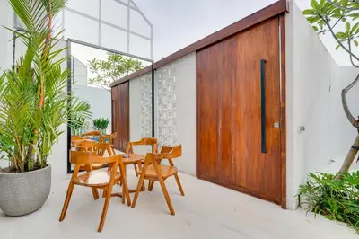 a patio with wooden doors and chairs and plants at Modern 2BR Villa Reisi Malindra M12 in Denpasar in Kerobokan