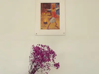 a picture hanging on a wall next to a vase with purple flowers at Villa Lilla and Sauna in Canggu