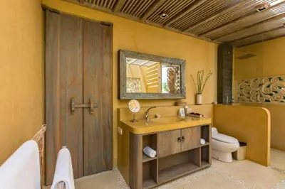 a bathroom with a sink and a toilet and a mirror at Kevia Peaceful 3 BR Private Pool Villa in Seminyak