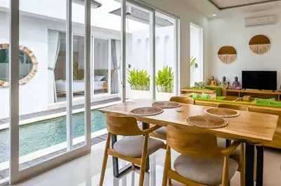 a dining room with a table and chairs and a living room at Luxurious Semeniyak new 2BR villa with a pool in Seminyak