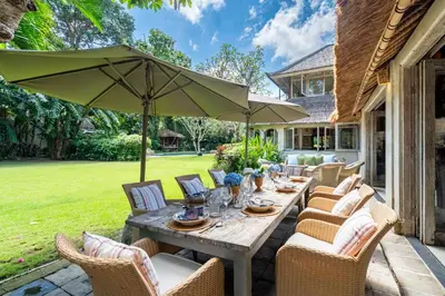 a table with chairs and an umbrella on a patio at The Orchard house Bali by Puri Asia in Seminyak