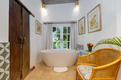 a large tub in a bathroom with a chair and a window at The Orchard house Bali by Puri Asia in Seminyak