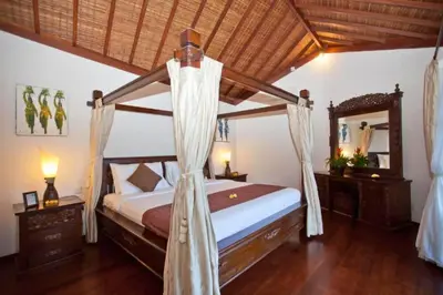 a bedroom with a canopy bed and a mirror at Philana Cozy 3 BR Private Pool Villa in Seminyak