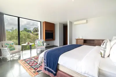 a bedroom with a large bed and a balcony at Santos Cliff View Jimbaran in Jimbaran