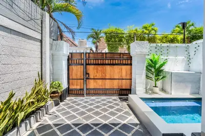 a backyard with a wooden gate and a swimming pool at Cening Villa Seminyak in Seminyak
