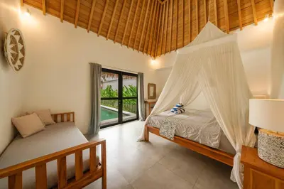 a bedroom with a bed with a mosquito net at Tropical 2BR Pool Villa near Seminyak & Canggu in Kerobokan
