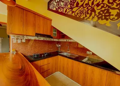a kitchen with wooden cabinets and a staircase in it at quiet and comfortable villa in sanur kauh in Sanur