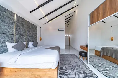 a bedroom with a large white bed with a black and white rug at Seminyak Loft 360 by Villas R Us in Seminyak