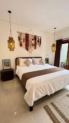 a bedroom with a large bed with clothes hanging on the wall at Villa Harmaka in Kerobokan