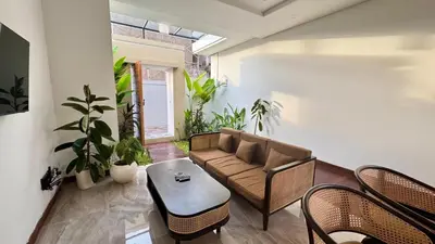 a living room with a couch and chairs and plants at Villa Harmaka in Kerobokan