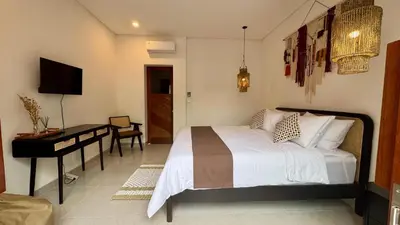a bedroom with a bed and a desk in it at Villa Harmaka in Kerobokan