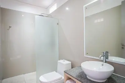 a bathroom with a sink and a toilet and a mirror at Harmony Beach Suite in Seminyak