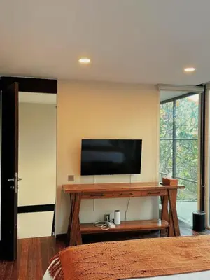 a room with a television on a wall with a table at Villa Jovino - Jameja By Island Villa Management in Kerobokan