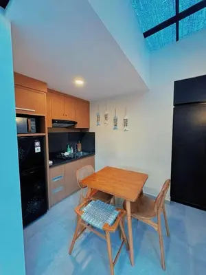 a kitchen with a wooden table and a black refrigerator at Villa Jovino - Jameja By Island Villa Management in Kerobokan