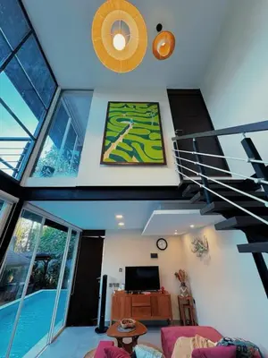 a living room with a spiral staircase and a television at Villa Jovino - Jameja By Island Villa Management in Kerobokan