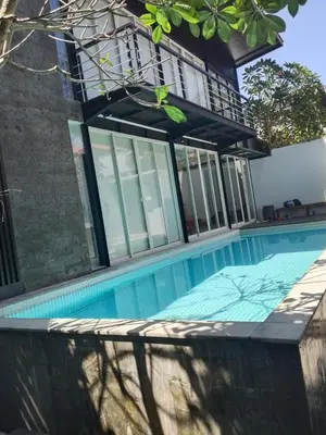 a swimming pool in front of a house at Villa Jovino - Jameja By Island Villa Management in Kerobokan