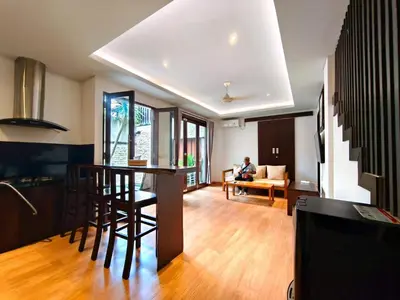 a kitchen and living room with a person sitting on a couch at Tahoma Villas Nakula by ABM in Legian