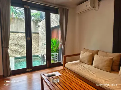 a living room with a couch and a large window at Tahoma Villas Nakula by ABM in Legian