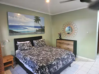 a bedroom with a bed and a painting on the wall at Jimmy's Hideaway at Mulia Cottages in Seminyak