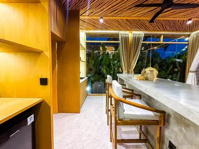 a kitchen with a long bar with chairs in a room at Desa Hut - Tropical Haven with Ricefield View near Seminyak in Kerobokan