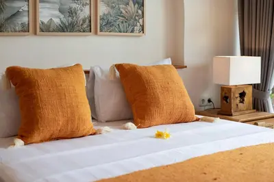 a bed with orange pillows and a yellow flower on it at NEW Villa Chim Chim Modern 2BR Tropical with Pool in Seminyak