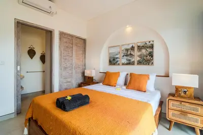 a bedroom with a large bed with an orange blanket at NEW Villa Chim Chim Modern 2BR Tropical with Pool in Seminyak