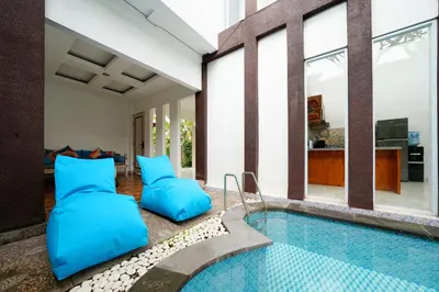 a house with a swimming pool with blue pillows at Mertasari Beach Villa Sanur - 3 BR in Sanur