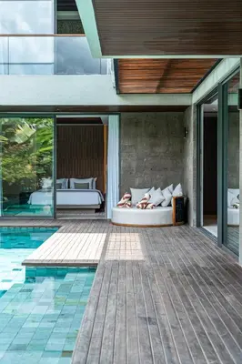 a woman laying on a bed next to a pool at Akar & Daun - NEW! 8BR Villa Haven, Near Berawa Beach! in Canggu
