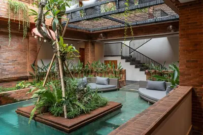 an indoor pool with chairs and plants in a building at Baliris Home Boutique Legian in Seminyak
