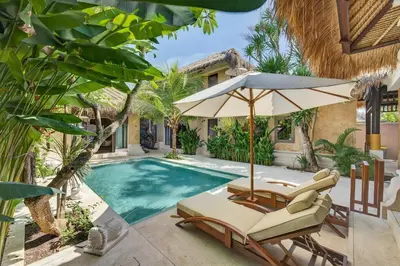 a swimming pool with two lounge chairs and an umbrella at Tropical 3BR Villa Private Pool in Jimbaran in Jimbaran